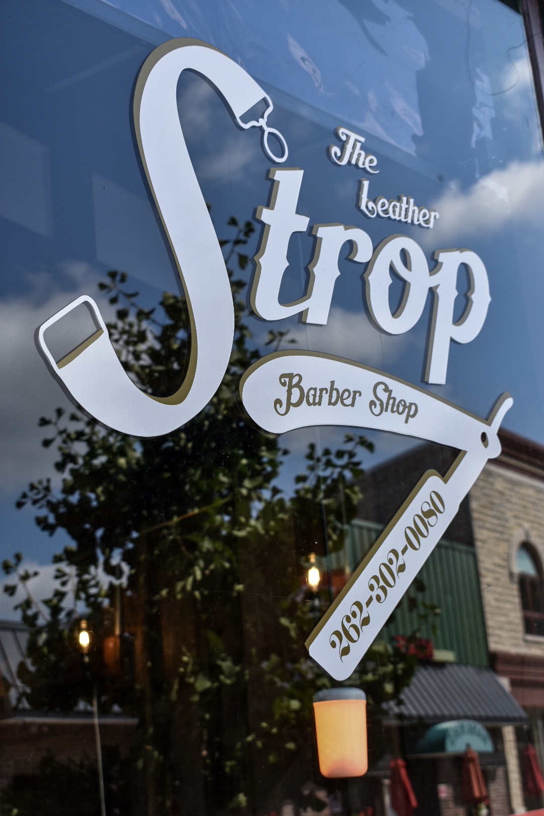 Barber giving a men's haircut at The Leather Strop Barbershop in Waukesha WI